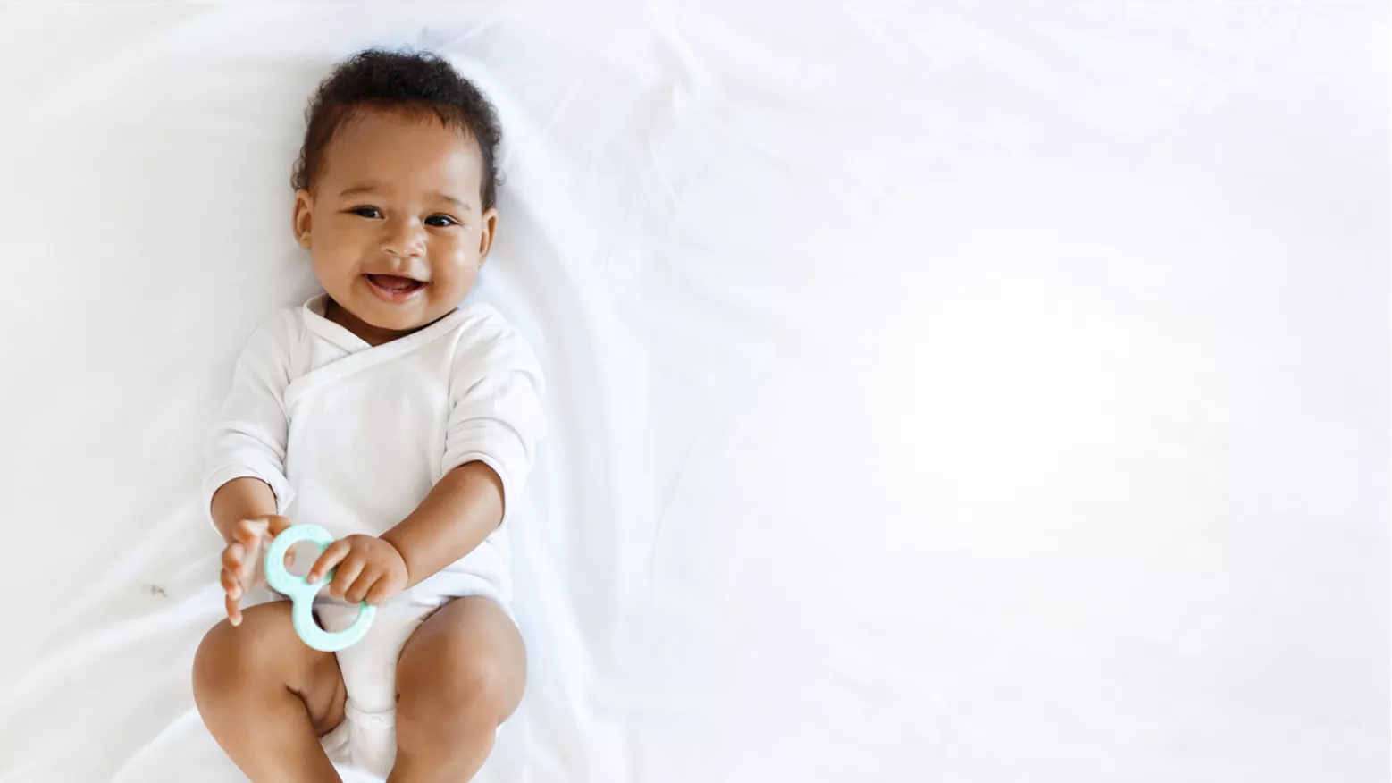 Happy baby holding teething toy at Blossom Nursery & Preschool infant programme