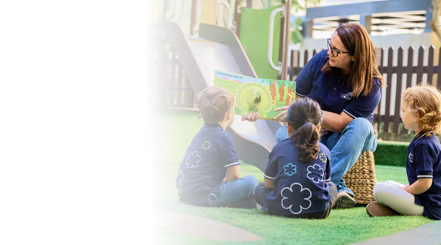 Early years educator smiling confidently outdoors while leading story time at Blossom Nursery & Preschool